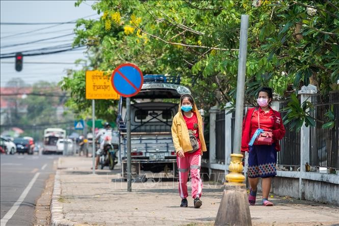 Người dân đeo khẩu trang nhằm ngăn chặn sự lây lan của dịch COVID-19 tại Viêng Chăn, Lào ngày 23/3. Ảnh: THX/TTXVN