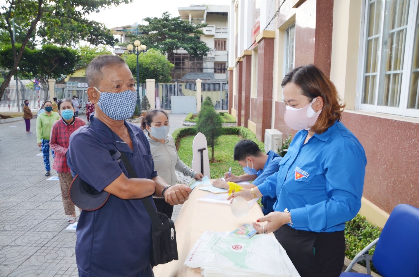 Người đến nhận gạo được yêu cầu rửa tay sát khuẩn và giữ khoảng cách an toàn.