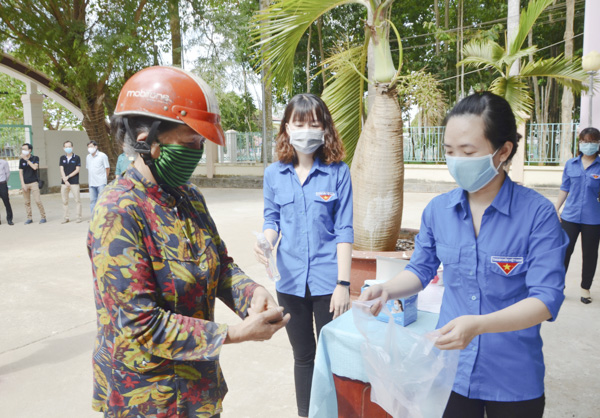 Người dân TP.Bà Rịa được hướng dẫn vệ sinh tay trước khi nhận gạo tại “ATM gạo”  xã Hòa Long.