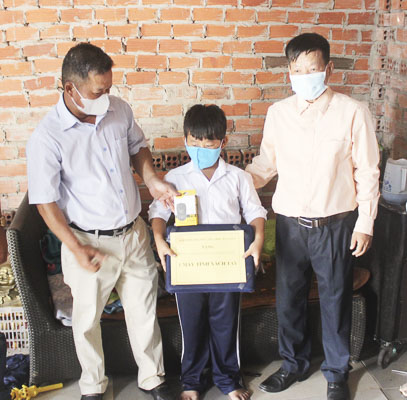 Đại diện Ban Giám hiệu và Hội cha mẹ HS Trường TH Hạ Long (TP. Vũng Tàu)  đến tặng máy tính xách tay cho em Trần Minh Hải, HS lớp 1E. 