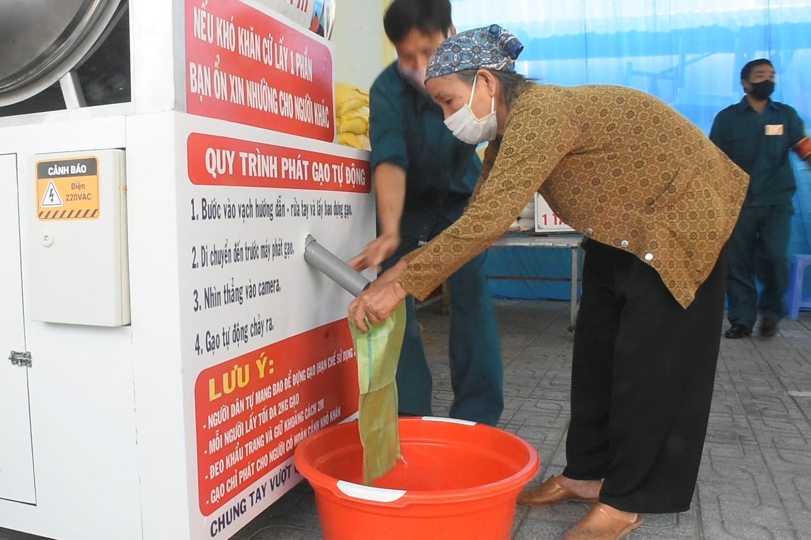 Lực lượng dân quân địa phương được huy động hỗ trợ người dân nhận gạo tại cây “ATM”.