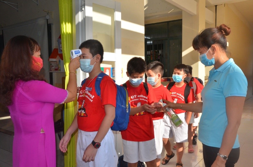 Giáo viên Trường TH Quang Trung (TP. Vũng Tàu) đo thân nhiệt và hướng dẫn HS rửa tay sát khuẩn trước khi vào lớp học. Ảnh: KHÁNH CHI