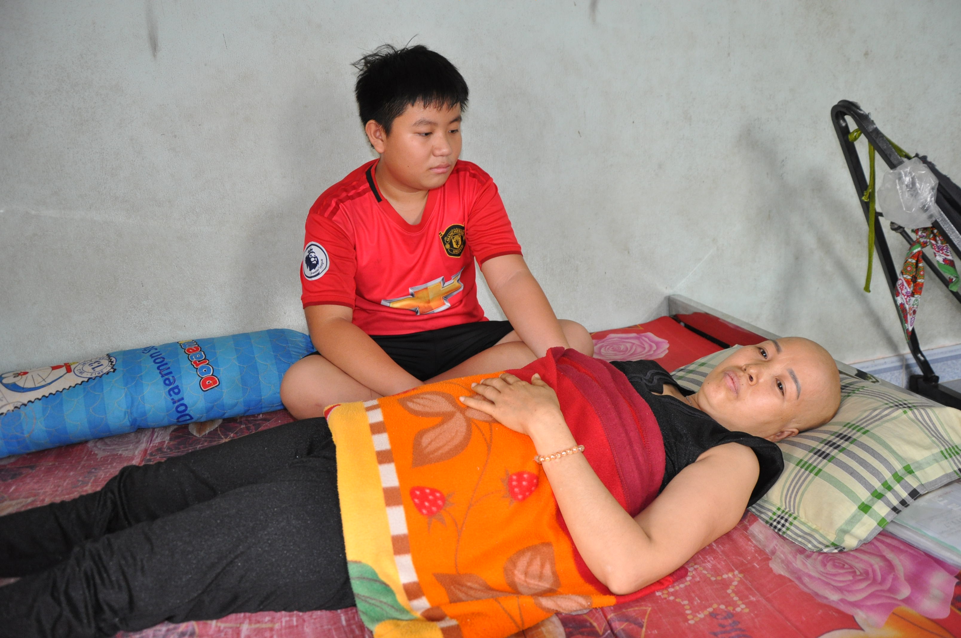 Em Nguyễn Văn Quốc chăm sóc mẹ đang bị hành hạ bởi những cơn đau của bệnh ung thư vú.
