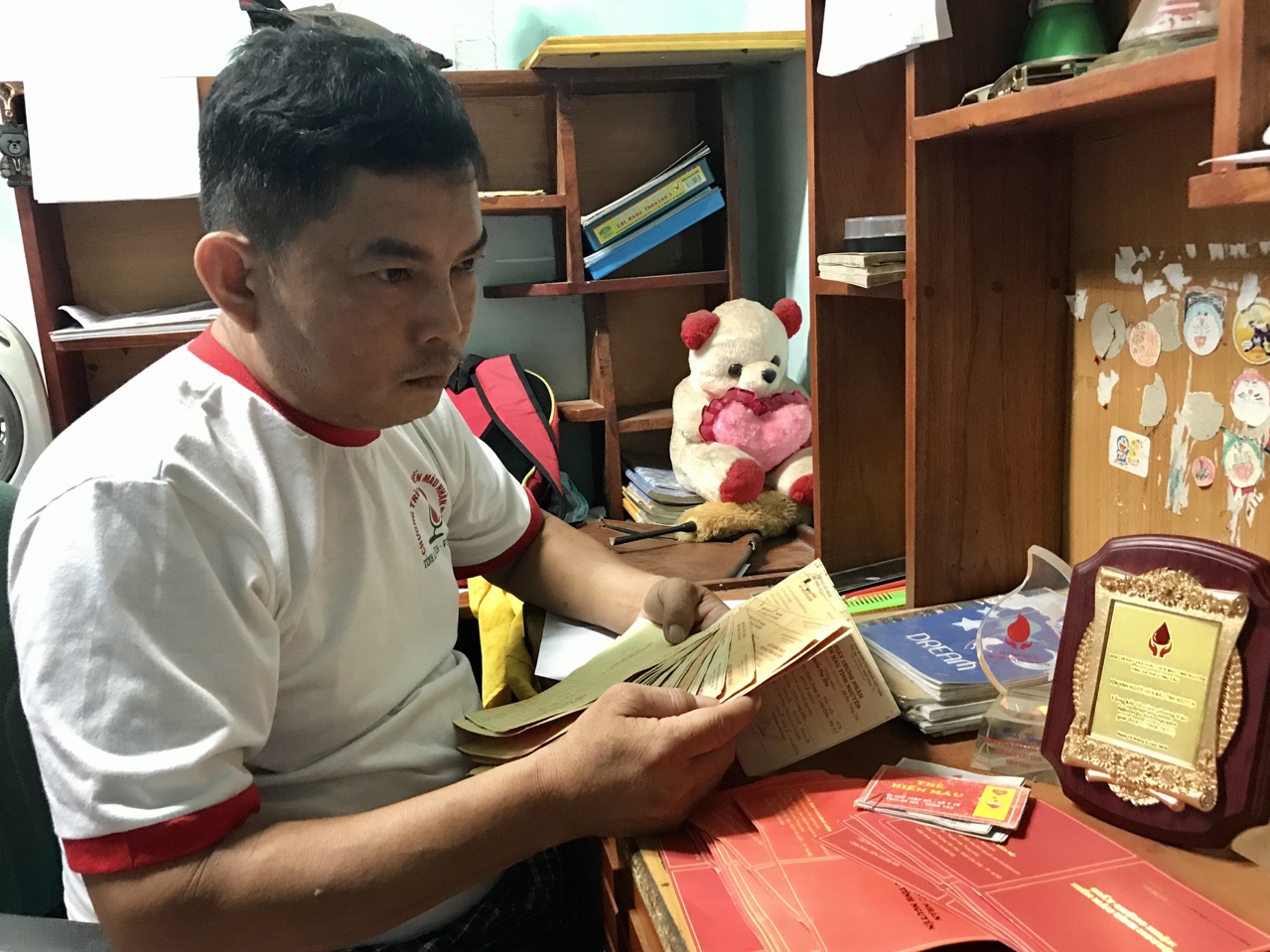 Anh Nguyễn Phú Hữu bên những tấm giấy chứng nhận và kỷ niệm chương ghi nhận thành tích hiến máu tình nguyện.