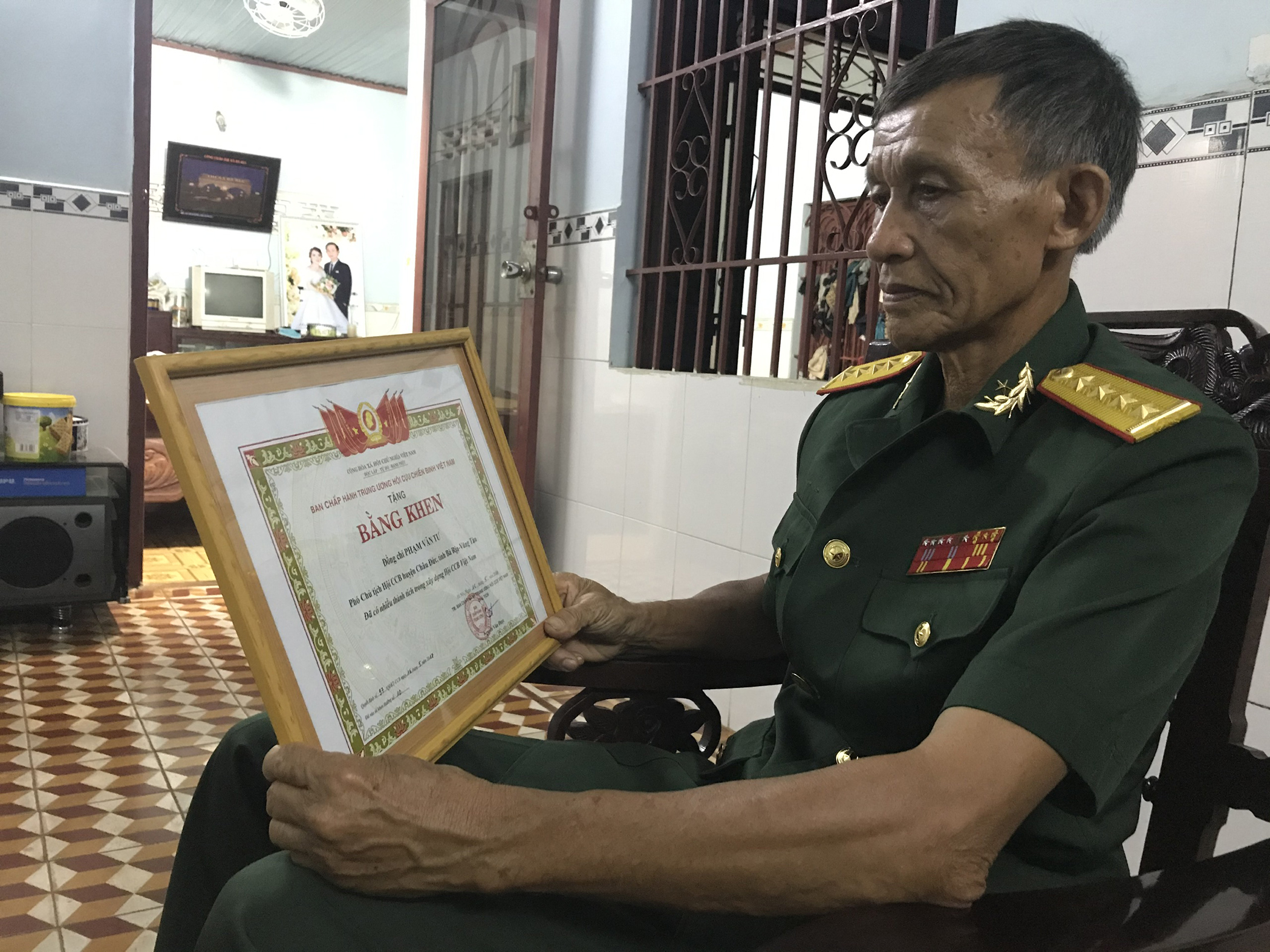 Thương binh Phạm Văn Tư nâng niu tấm Bằng khen của Trung ương Hội CCB Việt Nam ghi nhận những đóng góp của ông.