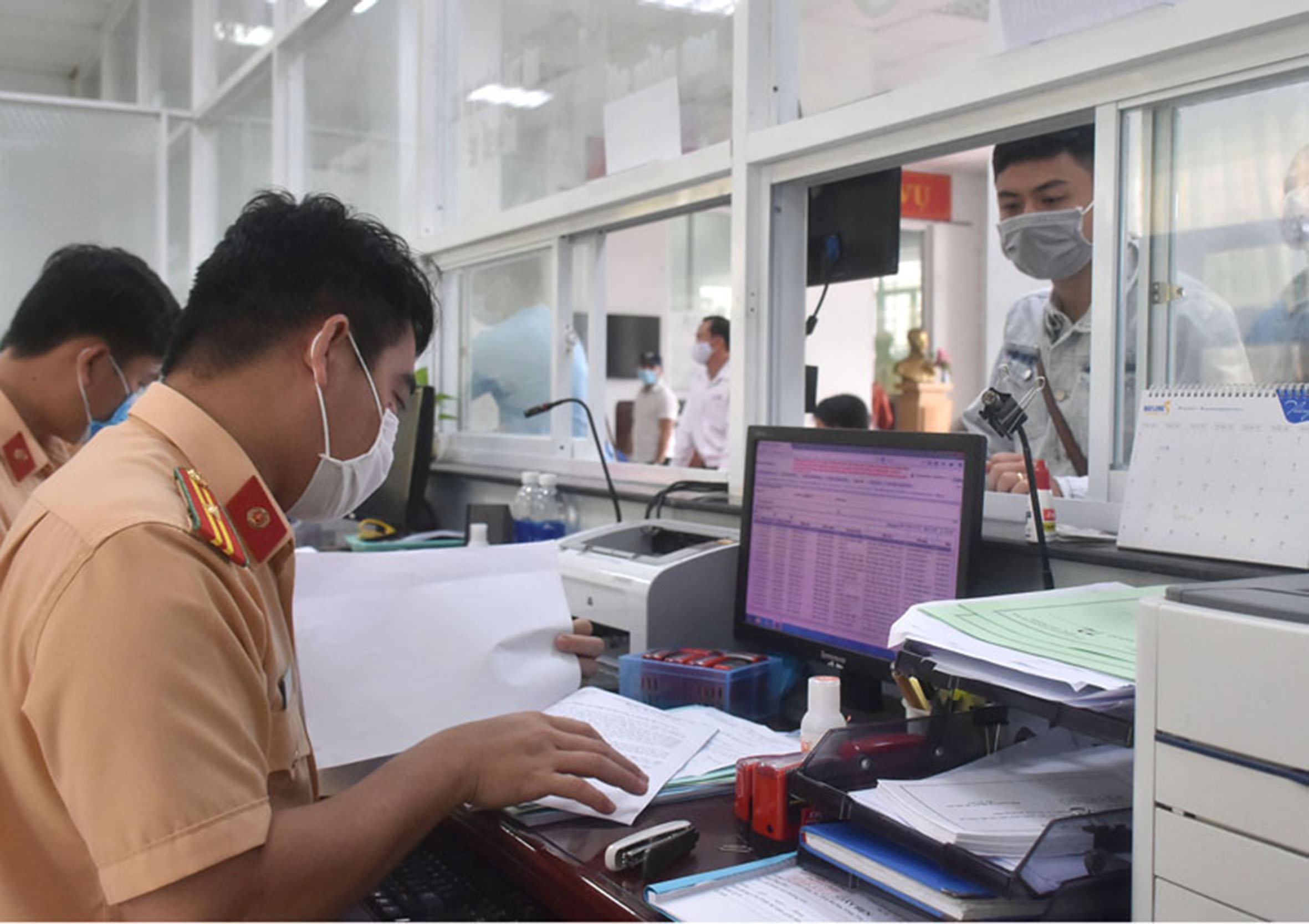 Cán bộ Phòng PC08 - Công an tỉnh tiếp nhận, giải quyết hồ sơ đăng ký xe cho người dân.