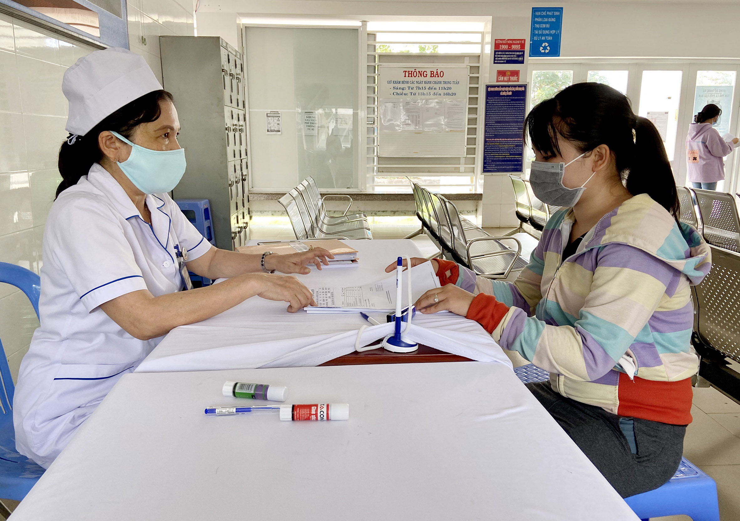 Chị Ngô Thị Nguyệt (bên phải, tổ 8, khu phố Hòa Hội, TT.Đất Đỏ) được nhân viên y tế của Trung tâm Y tế huyện Đất Đỏ hướng dẫn kê khai thông tin vào hồ sơ khám sức khỏe.
