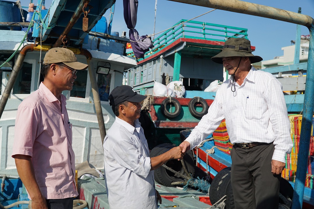 Ông Nguyễn Trính (bìa phải), Giám đốc HTX Dịch vụ khai thác thủy sản Quyết Thắng thăm hỏi, động viện thành viên trong HTX trước khi ra khơi khai thác thủy sản.
