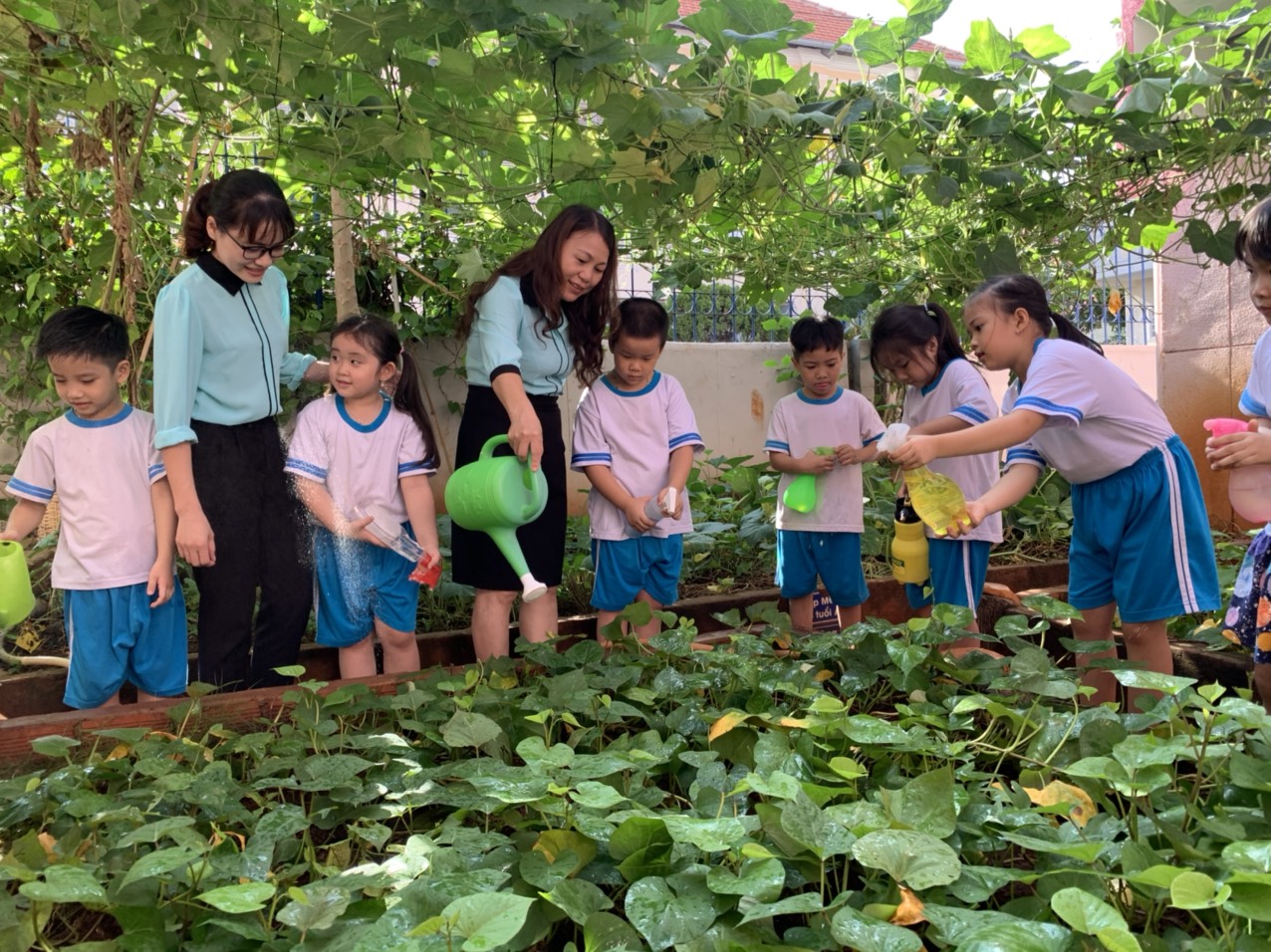 Cô Nguyễn Thị Phương, Hiệu trưởng Trường MN Ánh Dương cùng HS chăm sóc cây xanh trong trường. Ảnh: HUYỀN TRANG