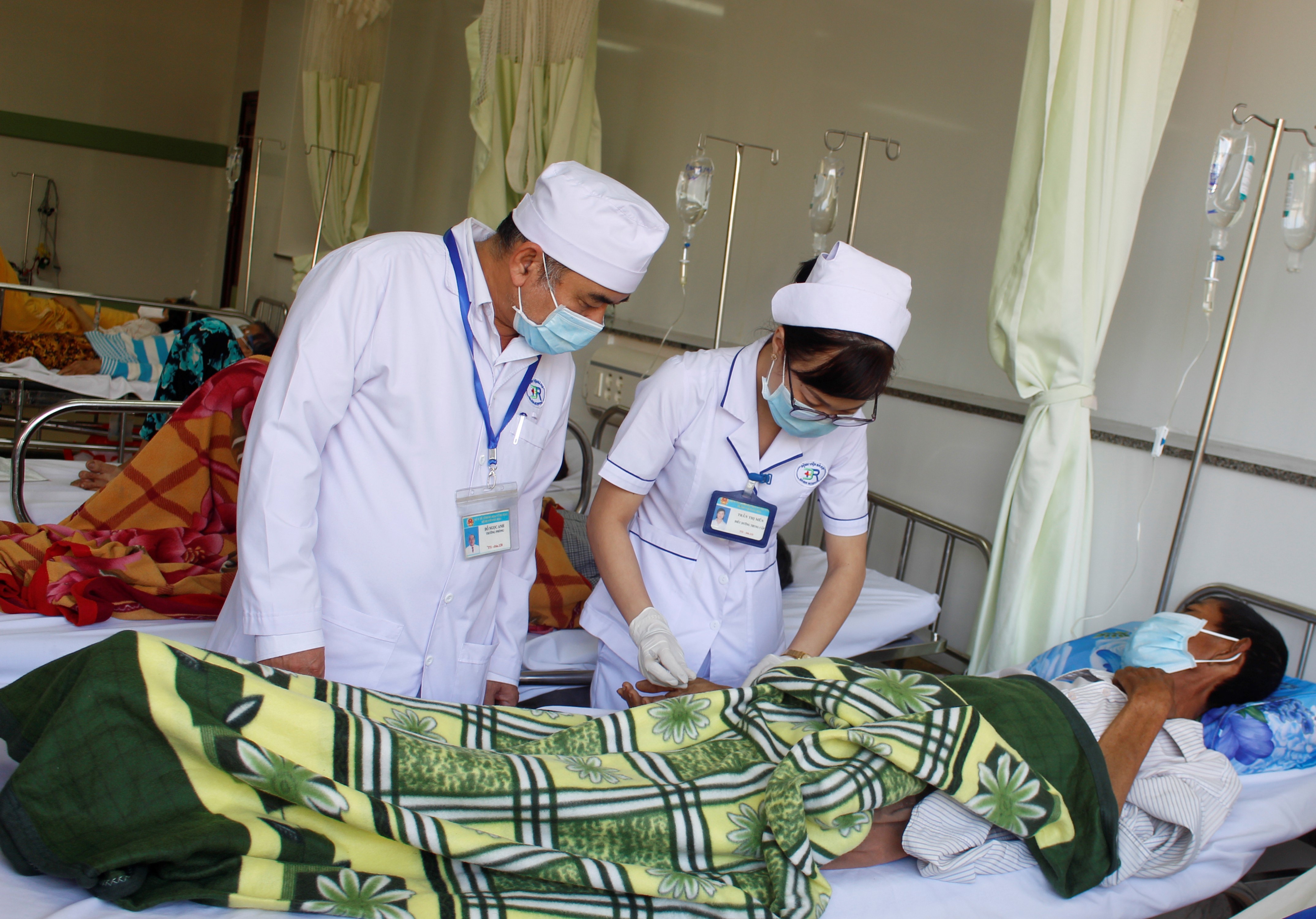 Điều dưỡng Đỗ Ngọc Anh (bìa trái), Trưởng Phòng Điều dưỡng (Bệnh viện Bà Rịa) hỗ trợ đồng nghiệp  chăm sóc bệnh nhân.