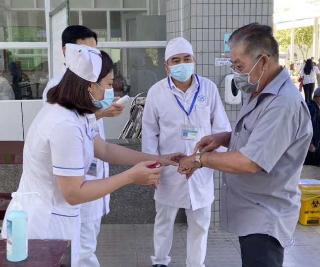 Người dân phải đeo khẩu trang ở nơi công cộng, nơi tập trung đông người. Trong ảnh: Nhân viên y tế kiểm tra thân nhiệt người vào Bệnh viện Bà Rịa.