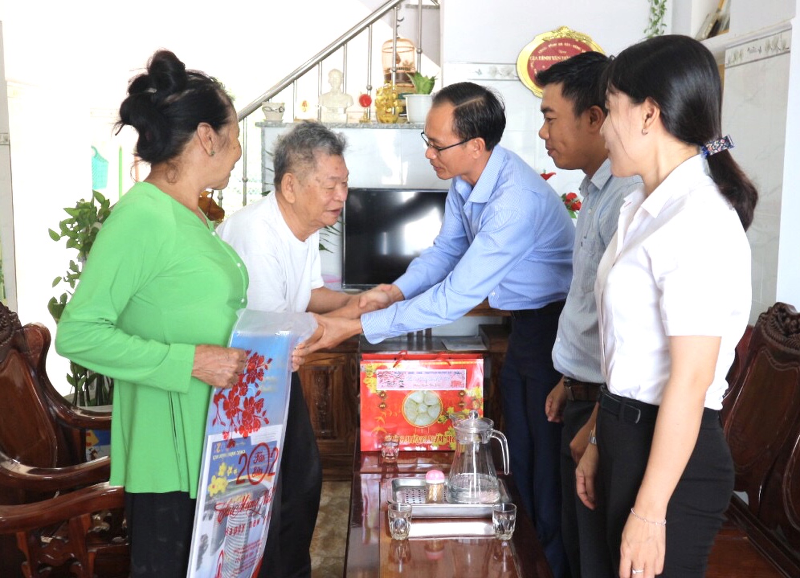 Ông Phan Minh Hợp, Bí thư Đảng uỷ phường Hắc Dịch thăm và tặng quà cho ông  Nguyễn Quang Trung (45 năm tuổi Đảng, ở khu phố 2). Ảnh: MỸ LƯƠNG