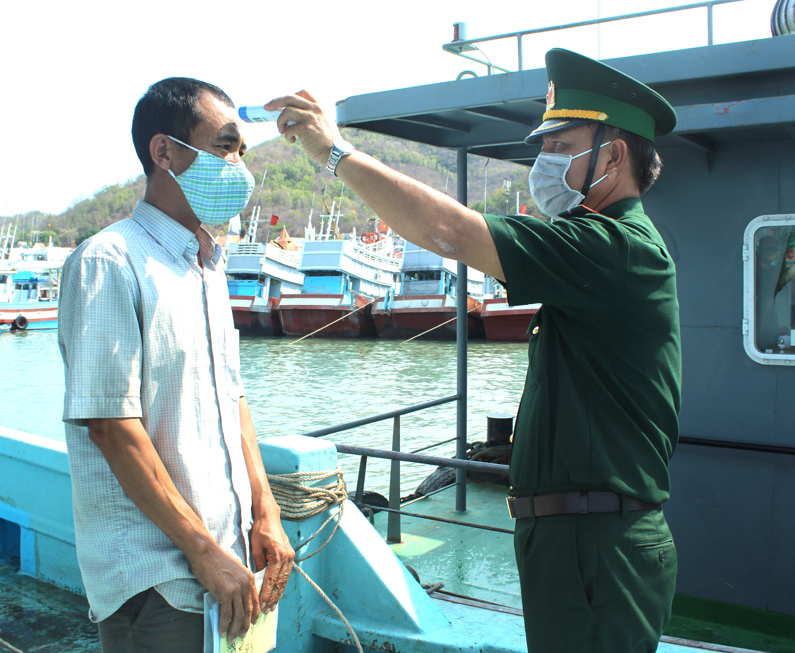 Lực lượng BĐBP tỉnh đo thân nhiệt cho ngư dân trước khi làm thủ tục xuất, nhập cảnh.