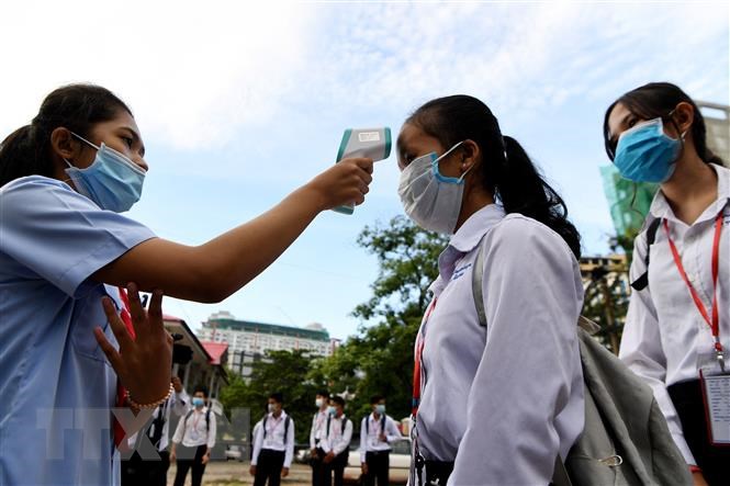Đo thân nhiệt phòng lây nhiễm COVID-19 tại một trường học ở Phnom Penh, Campuchia.