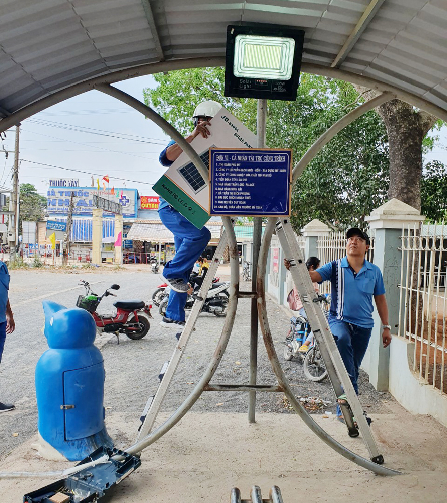 Nhân viên POSCO-Việt Nam lắp đèn năng lượng mặt trời tại nhà chờ cho HS trước Trường TH Mỹ Xuân (ấp Mỹ Tân, phường Mỹ Xuân, TX. Phú Mỹ).