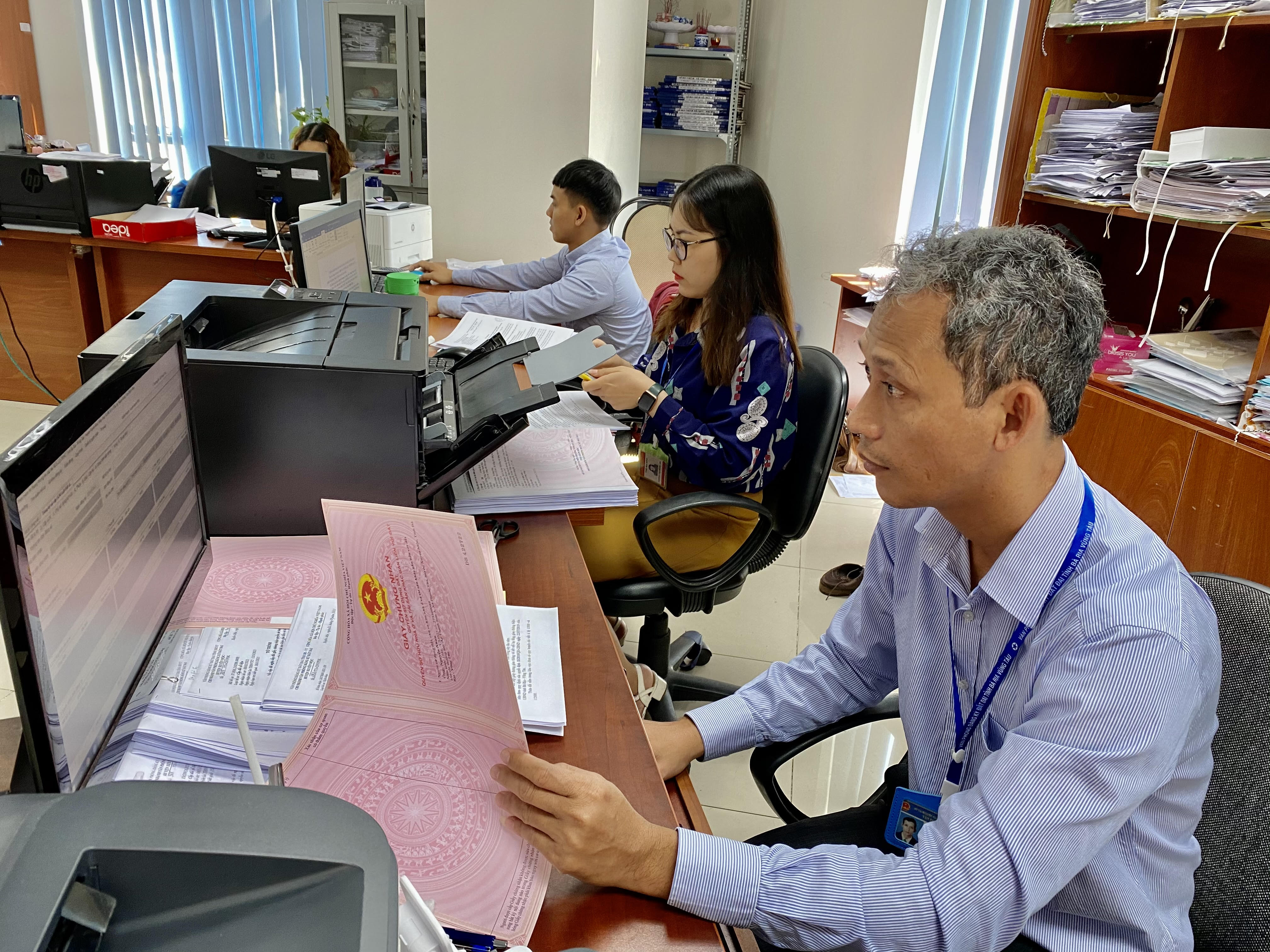 Viên chức Văn phòng Đăng ký đất đai tỉnh  làm thủ tục cấp sổ đỏ cho người dân tại trụ sở văn phòng.