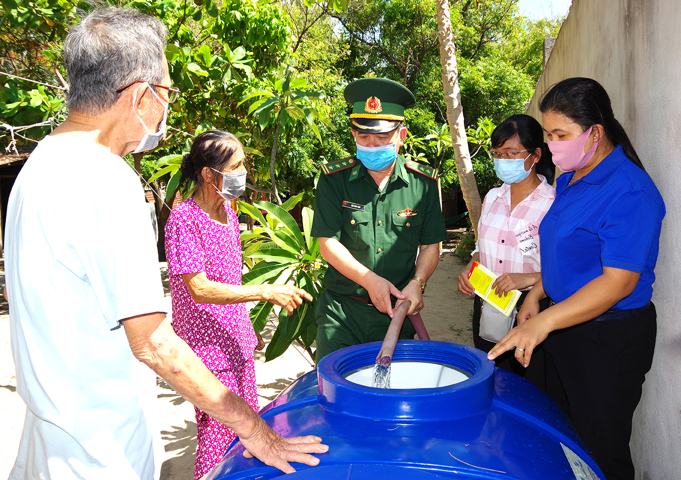 Cán bộ, chiến sĩ Đồn Biên phòng Chí Linh hướng dẫn gia đình bà Nguyễn Thị Ngọc Liên lấy nước sạch vào bồn chứa.  Ảnh: MINH NHÂN