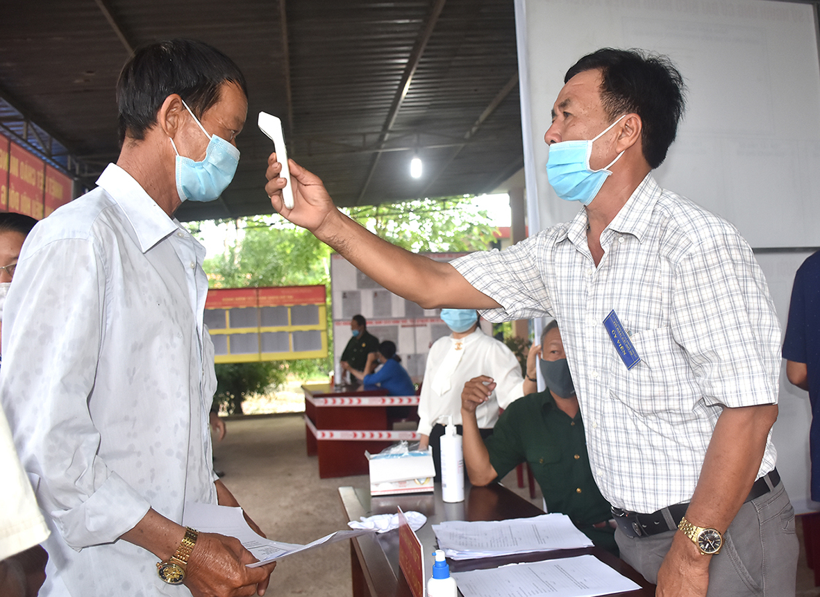 Cử tri tại khu vực bỏ phiếu số 5 ấp Thạnh Sơn 2A, xã Phước Thuận, huyện Xuyên Mộc đo than nhiệt, khai báo y tế trước khi vào khu vực bỏ phiếu. Ảnh: THÀNH HUY