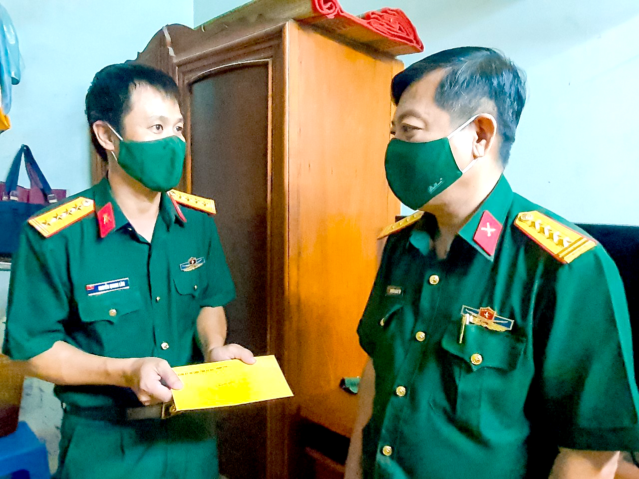 Đại tá Nguyễn Hoàng Tấn (phải), Phó Chính ủy Bộ CHQS tỉnh trao quà cho gia đình Đại úy Nguyễn Quang Lâm (Kho K694, Phòng Kỹ thuật Bộ CHQS tỉnh).