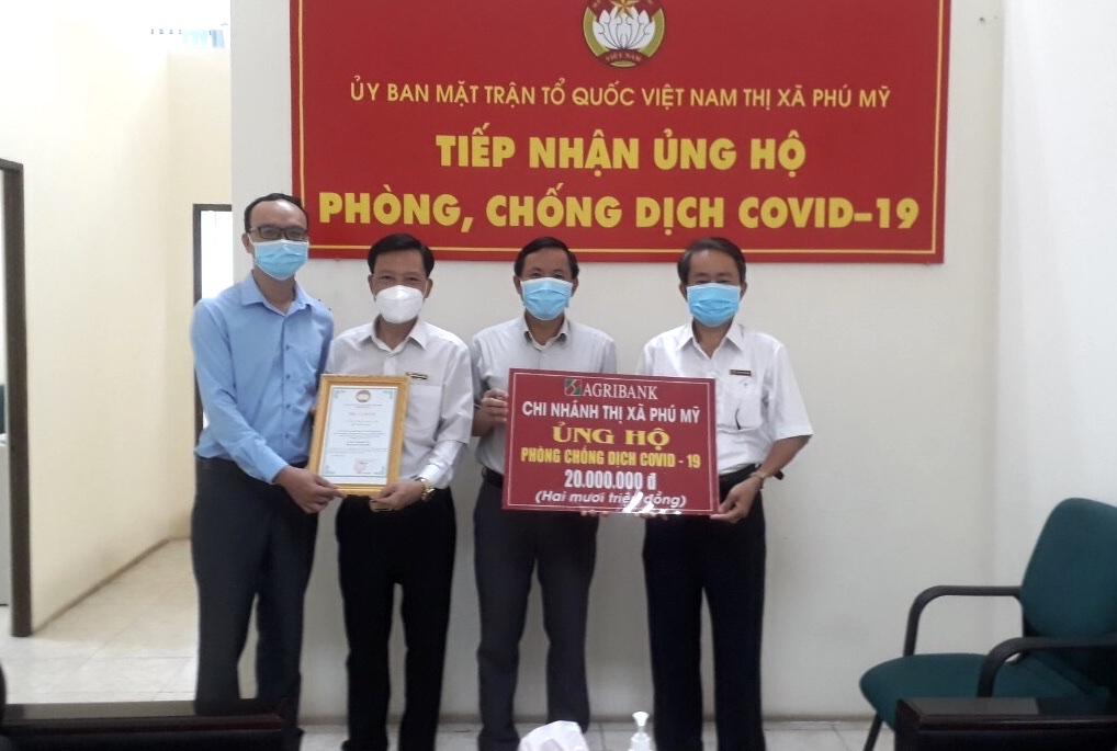 Ông Đặng Văn Minh, Phó Giám đốc Ngân hàng Agribank Chi nhánh Phú Mỹ (bìa phải) trao bảng tượng trưng số tiền 20 triệu đồng cho đại diện Ủy ban MTTQ Việt Nam TX.Phú Mỹ.