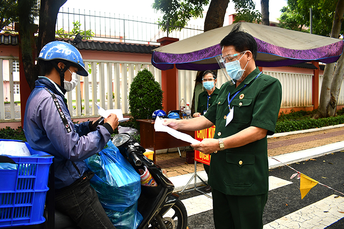  Ông Nguyễn Anh Võ (phải) kiểm tra giấy tờ người vào khu dân cư tại chốt kiểm soát dịch COVID-19 trên đường Pasteur.