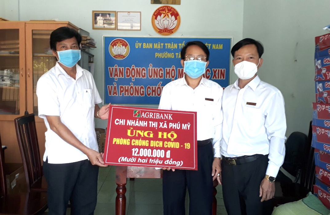 Ông Đặng Văn Minh, Phó giám đốc Agribank chi nhánh Phú Mỹ  (giữa) trao bảng tượng trưng số tiền 12 triệu đồng cho UBMTTQ Việt Nam phường Tân Phước (trái).