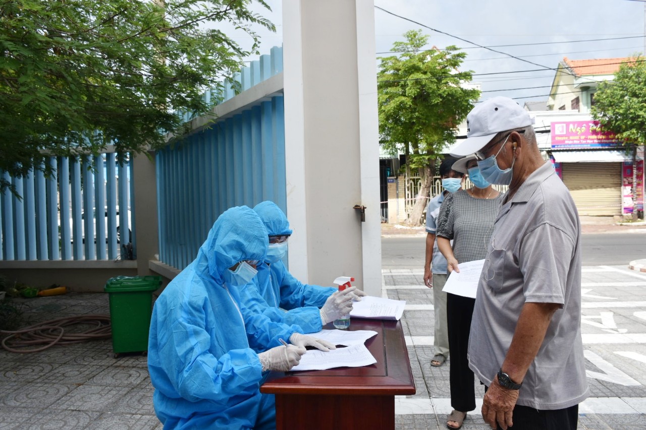 Người dân khu phố Hải Hà 1 được hướng dẫn khai báo y tế và sát khuẩn tay trước khi vào khu vực tiêm vắc xin phòng COVID-19