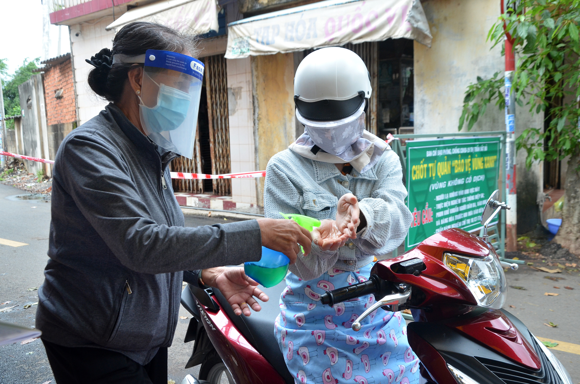 Bà Võ Thị Màu (Tổ trưởng tổ 11, KP. Phước Sơn, thị trấn Đất Đỏ,  huyện Đất Đỏ) sát khuẩn cho người dân ra, vào khu dân cư tại chốt tự quản “Bảo vệ vùng xanh” của tổ. Ảnh: VÂN ANH