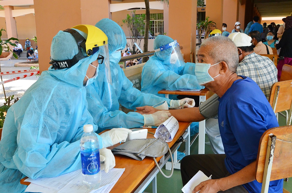 Nhân viên y tế đo huyết áp và tư vấn cho người đến tiêm vắc xin phòng COVID-19 tại điểm tiêm Trường THCS Huỳnh Khương Ninh, TP.Vũng Tàu. Ảnh: MINH THANH