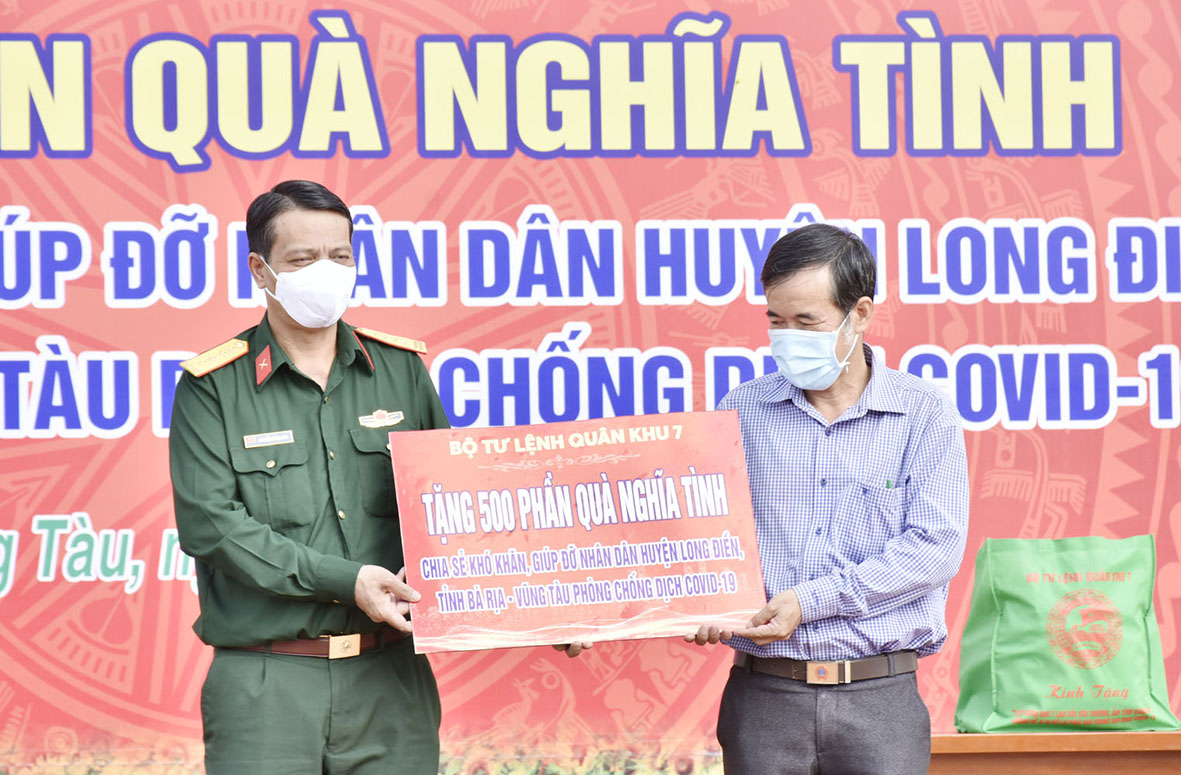 Đại tá Nguyễn Công Anh, Phó Chủ nhiệm Chính trị Quân khu 7 (bên trái) trao bảng tượng trưng tặng 500 phần quà cho đại diện Ủy ban MTTQ Việt Nan huyện Long Điền. 