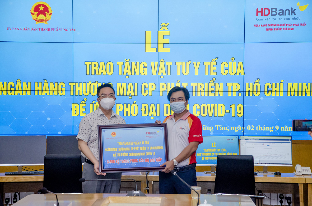 Đại diện Ngân hàng TMCP Phát triển TP. Hồ Chí Minh Chi nhánh Vũng Tàu (bên phải) trao bảng tượng trưng 3.600 bộ đồ bảo hộ y tế cho TP.Vũng Tàu để phục vụ công tác phòng, chống dịch COVID-19.