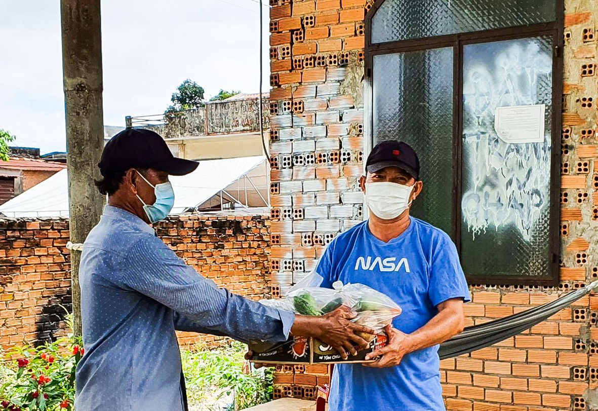 Ông Lê Tâm (bên trái), Trưởng Ban điều hành ấp 2B, xã Bàu Lâm trao túi an sinh cho người dân có hoàn cảnh khó khăn trên địa bàn ấp.