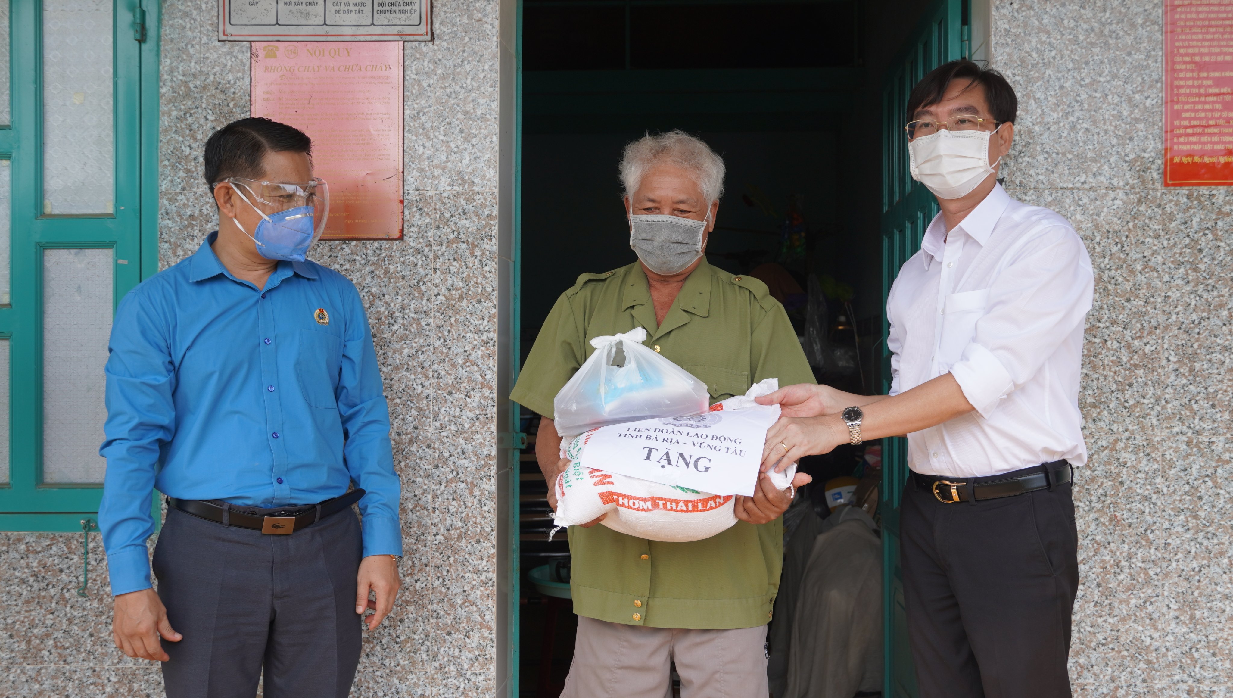 Ông Huỳnh Sơn Tuấn (trái), Chủ tịch LĐLĐ tỉnh cùng ông Nguyễn Trường Giang (phải), Phó Bí thư Đảng ủy Khối Cơ quan và Doanh nghiệp tỉnh trao quà cho lao động tự do ở trọ trên địa bàn huyện Đất Đỏ.