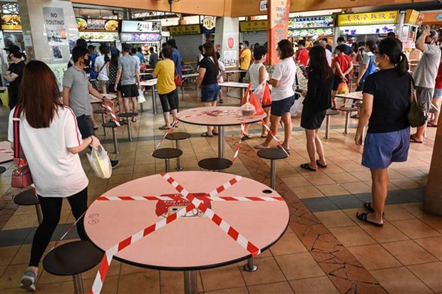 Người dân xếp hàng mua đồ ăn mang về để phòng lây nhiễm COVID-19 tại Singapore.