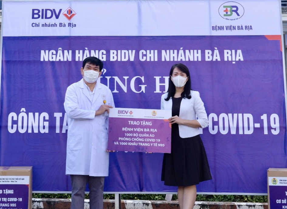 Bà Nguyễn Thanh Thủy, Giám đốc BIDV, Chi nhánh Bà Rịa trao bảng tượng trưng tặng quần áo bảo hộ và khẩu trang cho đại diện Bệnh viện Bà Rịa.