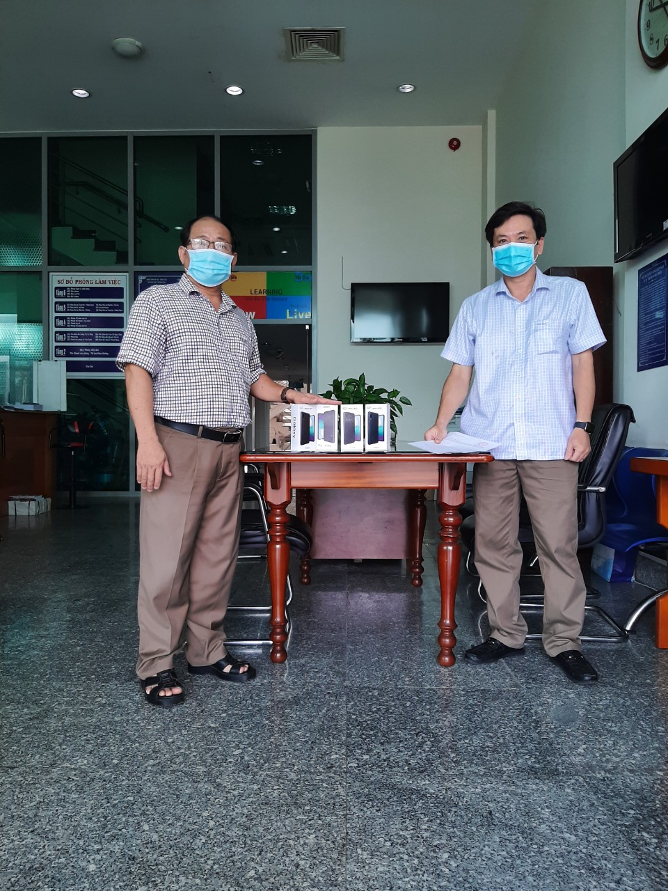 Ông Lê Văn Tuyền, Chánh Văn phòng Sở GD-ĐT (trái) bàn giao thiết bị thông minh cho đại diện Trung tâm GDTX tỉnh.