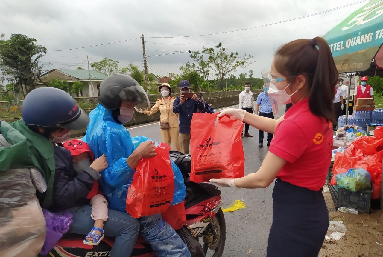 Trao tặng thức ăn và đồ dùng cho những người trở về bằng xe máy từ các tỉnh, thành phía Nam trên Quốc lộ 1A đoạn qua xã Hải Chánh, huyện Hải Lăng, tỉnh Quảng Trị. Ảnh: TTXVN