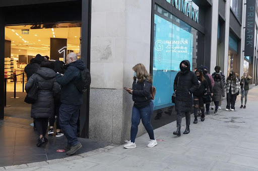 Người dân xếp hàng bên ngoài một cửa hàng ở London (Anh).