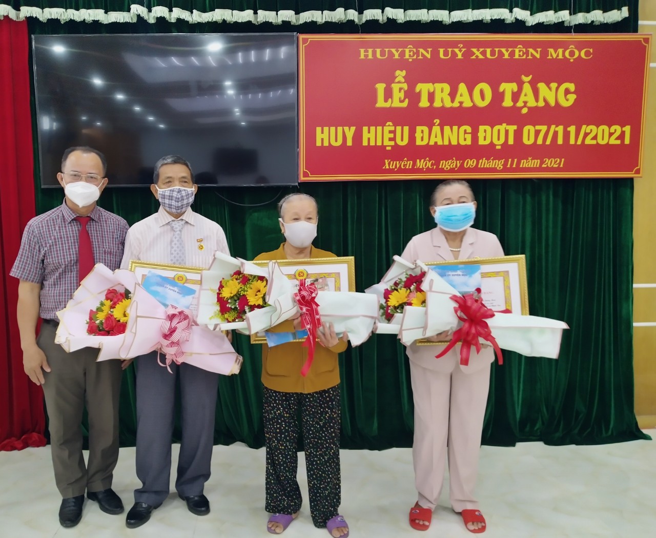 Ông Huỳnh Kim Sơn (bìa trái), Phó Bí thư Thường trực Huyện ủy Xuyên Mộc trao Huy hiệu 55 tuổi Đảng và tặng hoa chúc mừng 3 đảng viên.