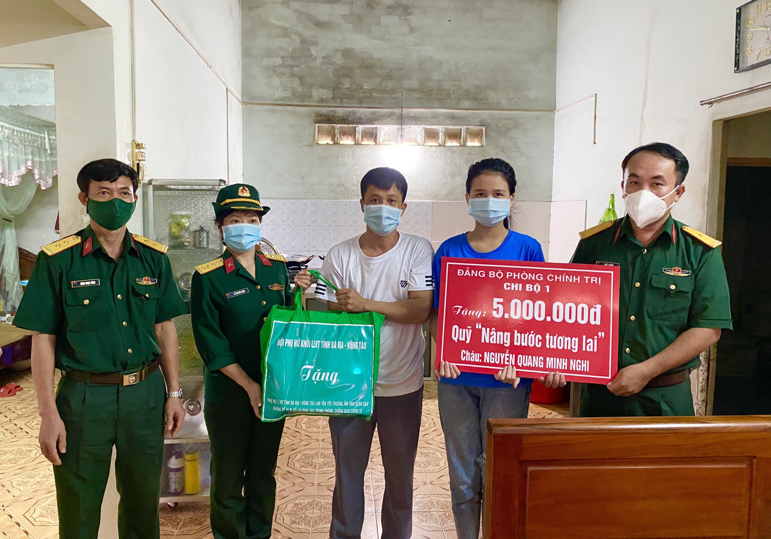 Đại diện Chi bộ 1, Đảng bộ Phòng Chính trị - Bộ CHQS tỉnh (bên phải) trao bảng tượng trưng nhận đỡ đầu đến hết lớp 12 cho em Nguyễn Quang Minh Nghi.