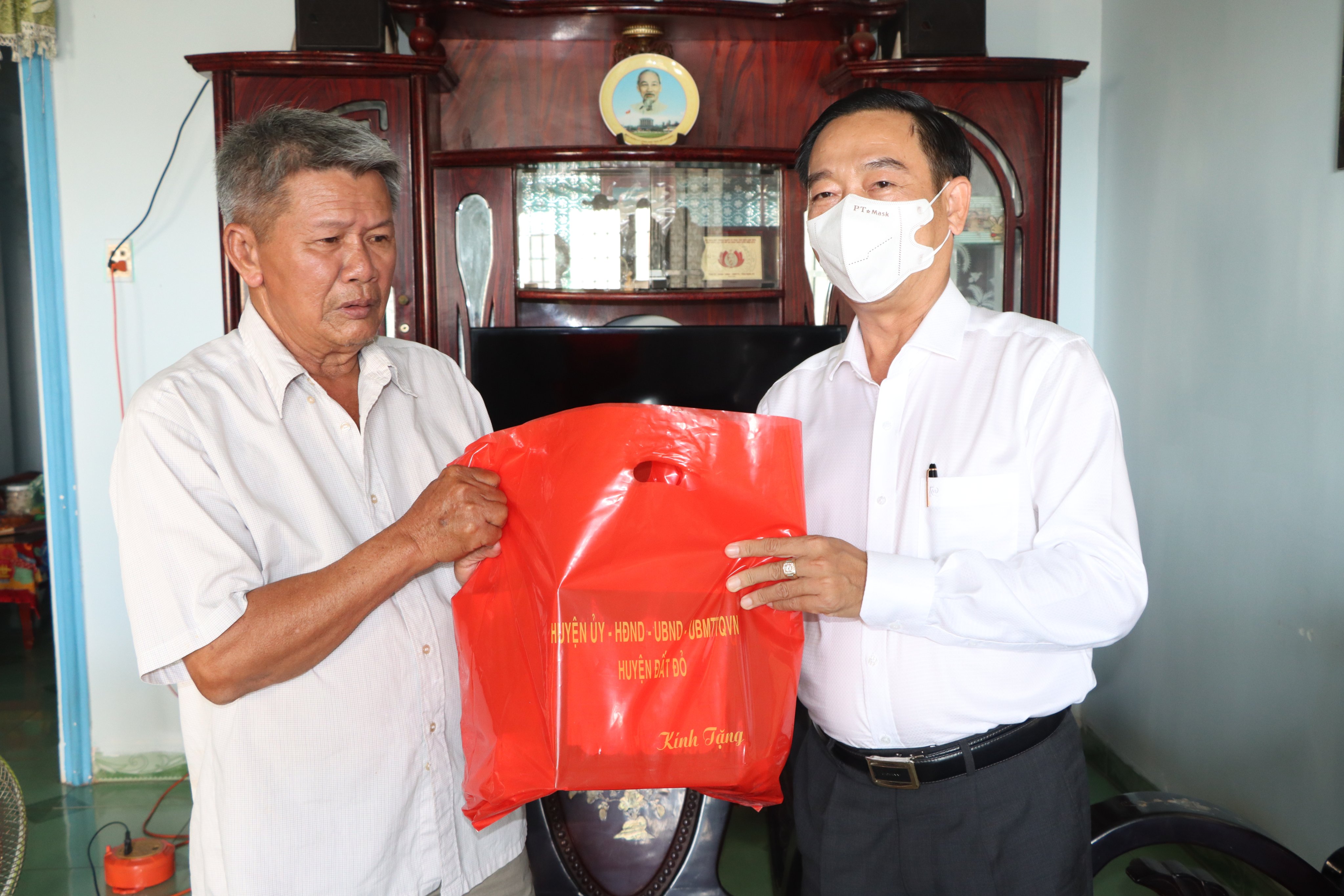 Ông Lê Văn Hòa, Bí thư Huyện ủy Đất Đỏ tặng quà cho ông Nguyễn Văn Bình, nguyên Quyền Tham mưu trưởng,  Ban CHQS huyện Long Đất. Ảnh: TUẤN VŨ