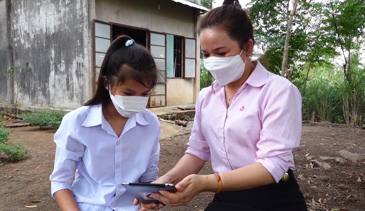 Bà Trần Thị Ngọc, Phó Giám đốc Phòng Giao dịch NHCSXH huyện Châu Đức hướng dẫn em Nguyễn Thị Thủy Tiên cách sử dụng Ipad.