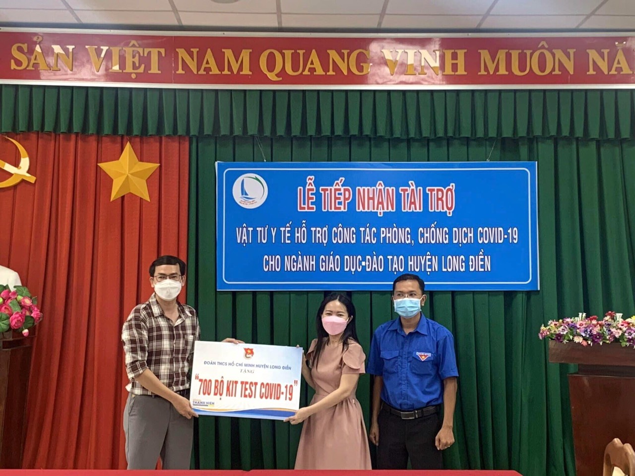 Anh Đỗ Minh Tân, Bí thư Huyện Đoàn Long Điền (trái) trao tặng bảng tượng trưng 700 bộ kit test tới lãnh đạo Phòng GD- ĐT huyện.