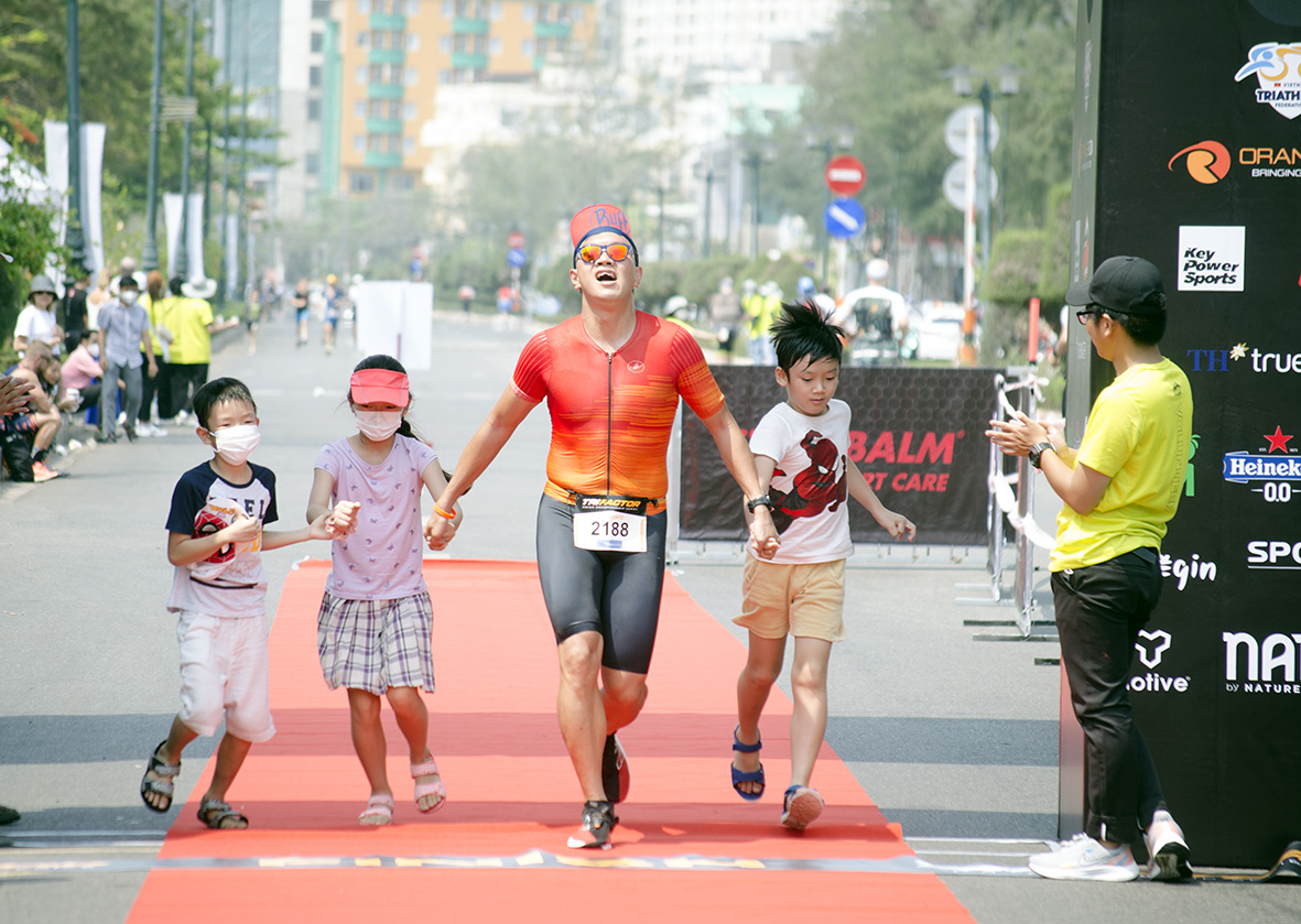 Một VĐV cùng gia đình phấn khích khi hoàn thành phần thi cuối cùng là chạy bộ để về đích.