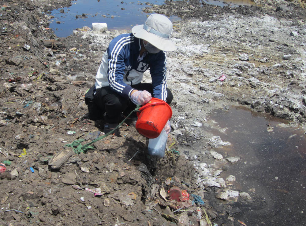Lực lượng chức năng lấy mẫu nước tại bãi chôn lấp rác tạm Phước Cơ.