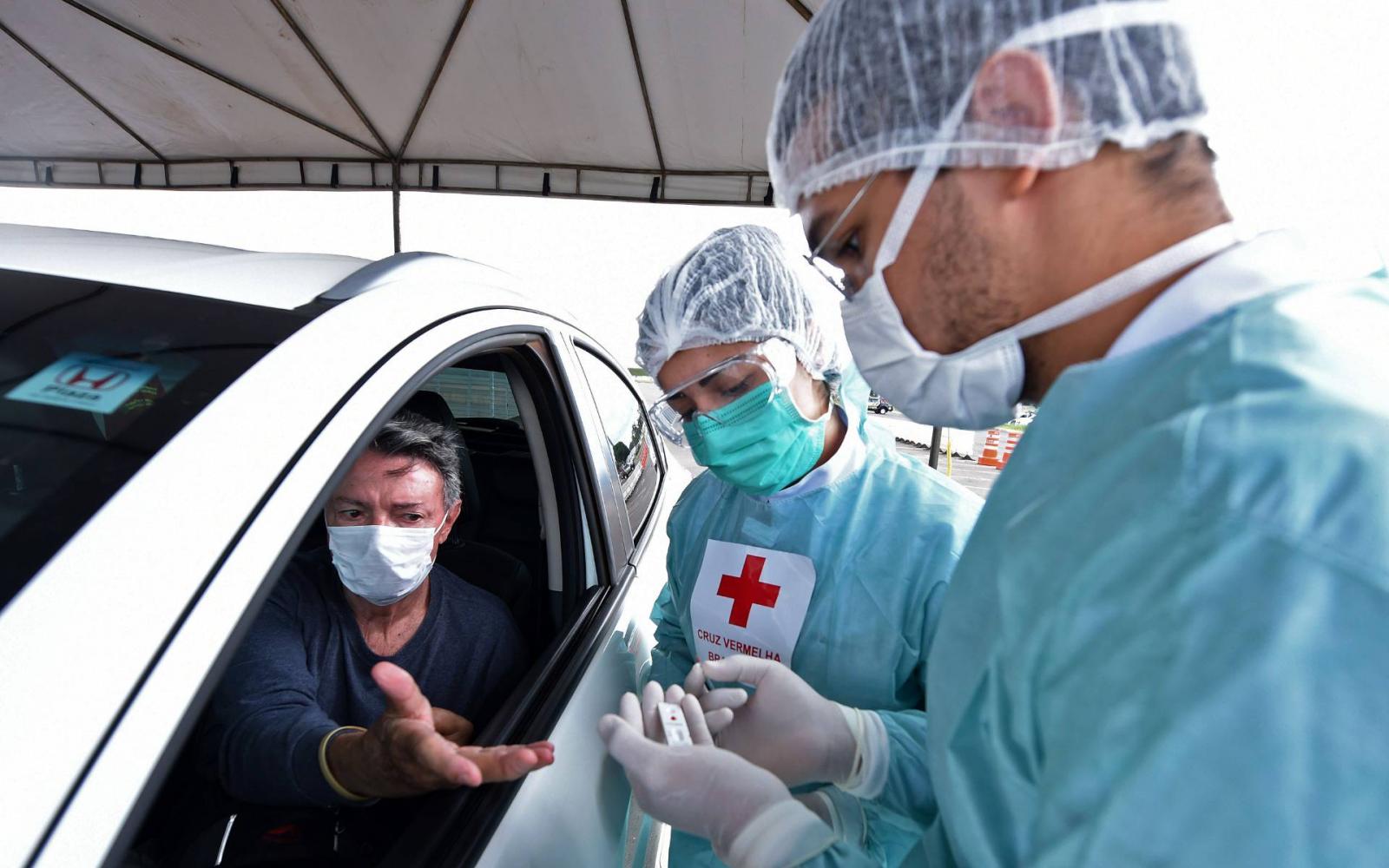 Nhân viên y tế xét nghiệm nhanh COVID-19 cho người dân tại một bãi đỗ xe ở Brasilia, Brazil.