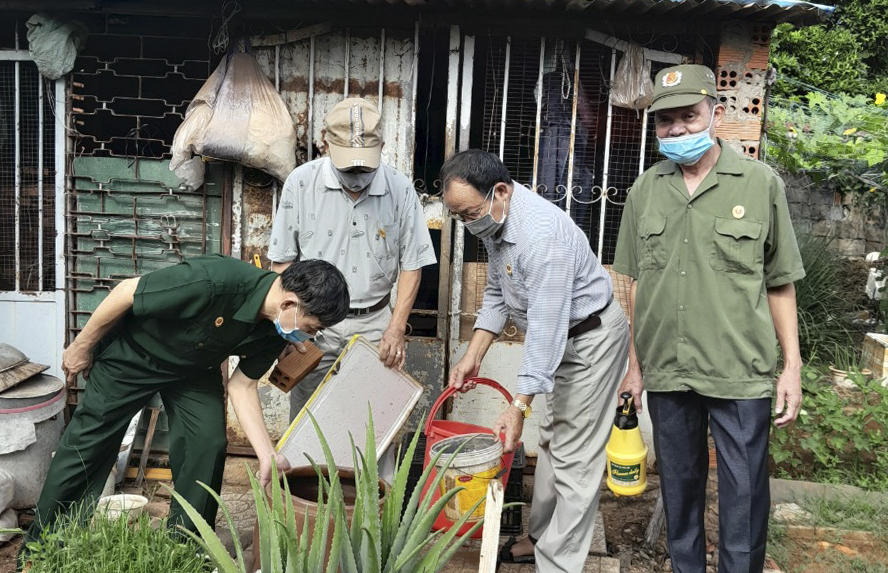 Hội viên Hội CCB phường Thắng Nhất tham gia vệ sinh dụng cụ chứa nước có bọ gậy giúp người dân.