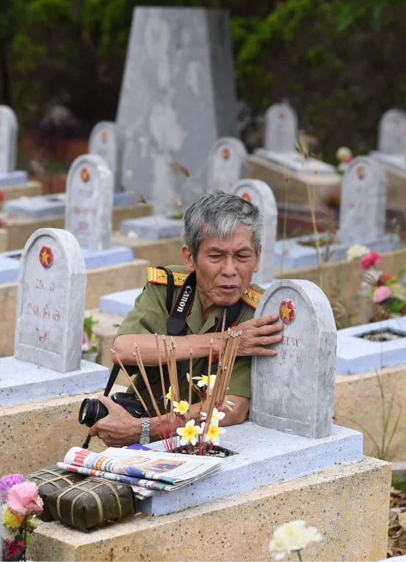 Nghệ sĩ nhiếp ảnh, Đại tá Trần Văn Hồng (Trần Hồng) bên mộ liệt sĩ Lê Đình Dư, nhà báo chiến trường (nguyên PV báo QĐND) - tại Nghĩa trang liệt sĩ Gio Linh (Quảng Trị), tháng 7/2022.