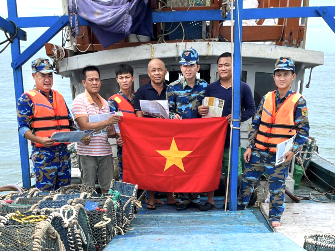 Cán bộ, chiến sĩ Hải đoàn Biên phòng 18 tuyên truyền pháp luật và tặng cờ Tổ quốc cho ngư dân.