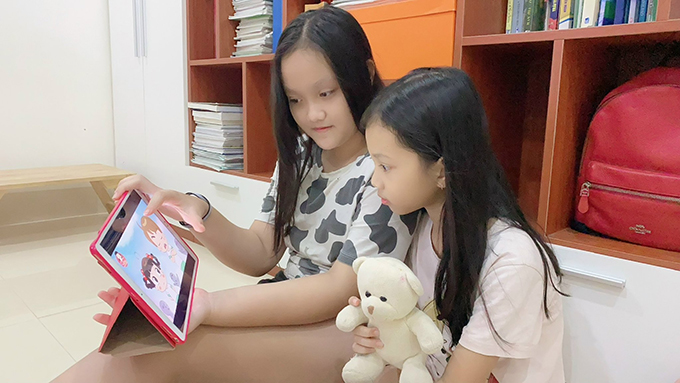 Hai em nhỏ xem phim hoạt hình trên ipad từ một kênh của truyền hình OTT.